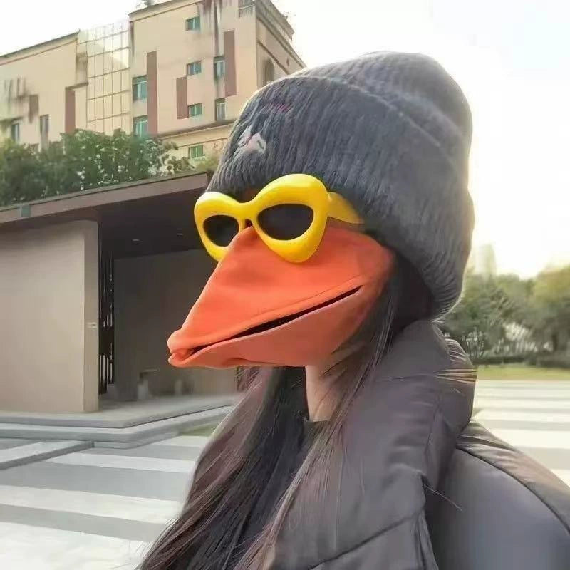 Side profile of woman wearing orange movable beak mask with yellow glasses
